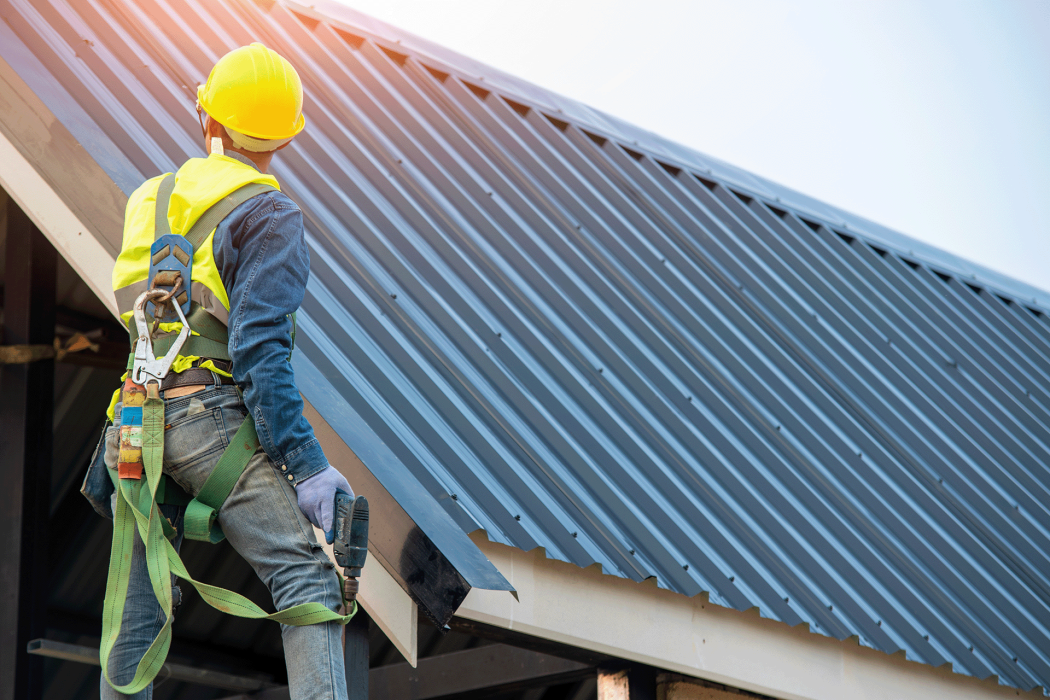 Roofer worker in protective uniform wear and gloves using air or pneumatic nail gun and installing asphalt shingle on top of the new roofConcept of residential building under construction